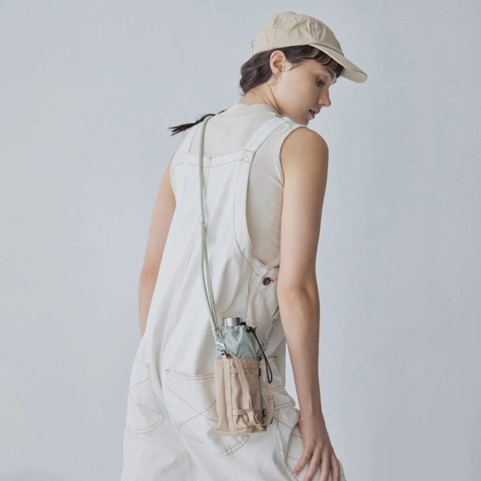 Person wearing a beige vest and cap with a Bitplay Waterproof Bottle Carrier 305D CORDURA 210D Nylon Ripstop Pouch with Lanyard Strap, standing against a plain background