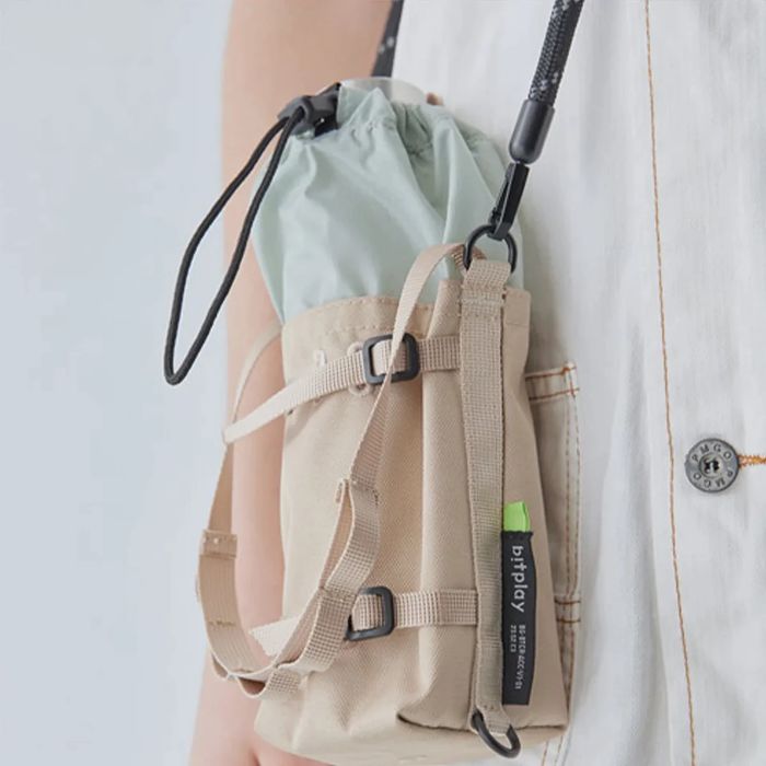 Sand Beige Bitplay Waterproof Bottle Carrier 305D CORDURA 210D Nylon Ripstop Pouch with Lanyard Strap worn by a person.