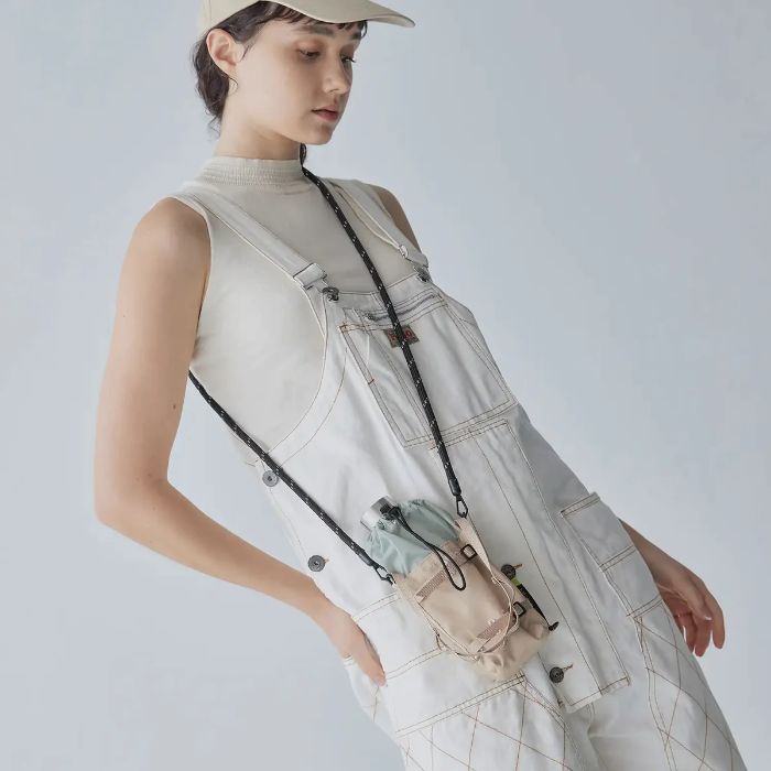 Person wearing a light-colored overalls with a Bitplay Waterproof Bottle Carrier 305D CORDURA 210D Nylon Ripstop Pouch with Lanyard Strap on a plain background
